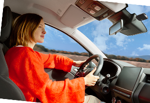 Personne conduisant une voiture, vue depuis l’intérieur avec paysage visible à travers le pare-brise.