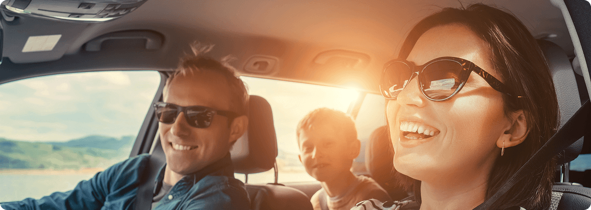 Personnes à l’intérieur d’une voiture en trajet, avec un adulte au volant, un passager à l’avant et un enfant à l’arrière.
