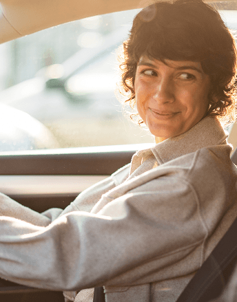 Personnes assises à l’avant d’une voiture, vues de l’intérieur, avec lumière du jour entrant par les vitres.