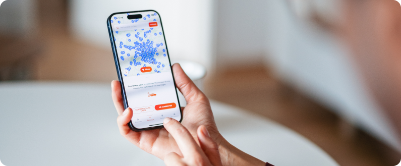 Personne tenant un smartphone affichant une application avec une carte et des points de localisation.