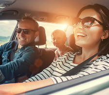 Personnes à l’intérieur d’une voiture en circulation, vues depuis l’extérieur, avec un passager à l’arrière et lumière du jour.