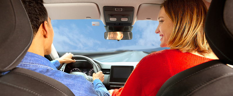 Personnes assises à l’avant d’une voiture en circulation, vues depuis l’arrière de l’habitacle.